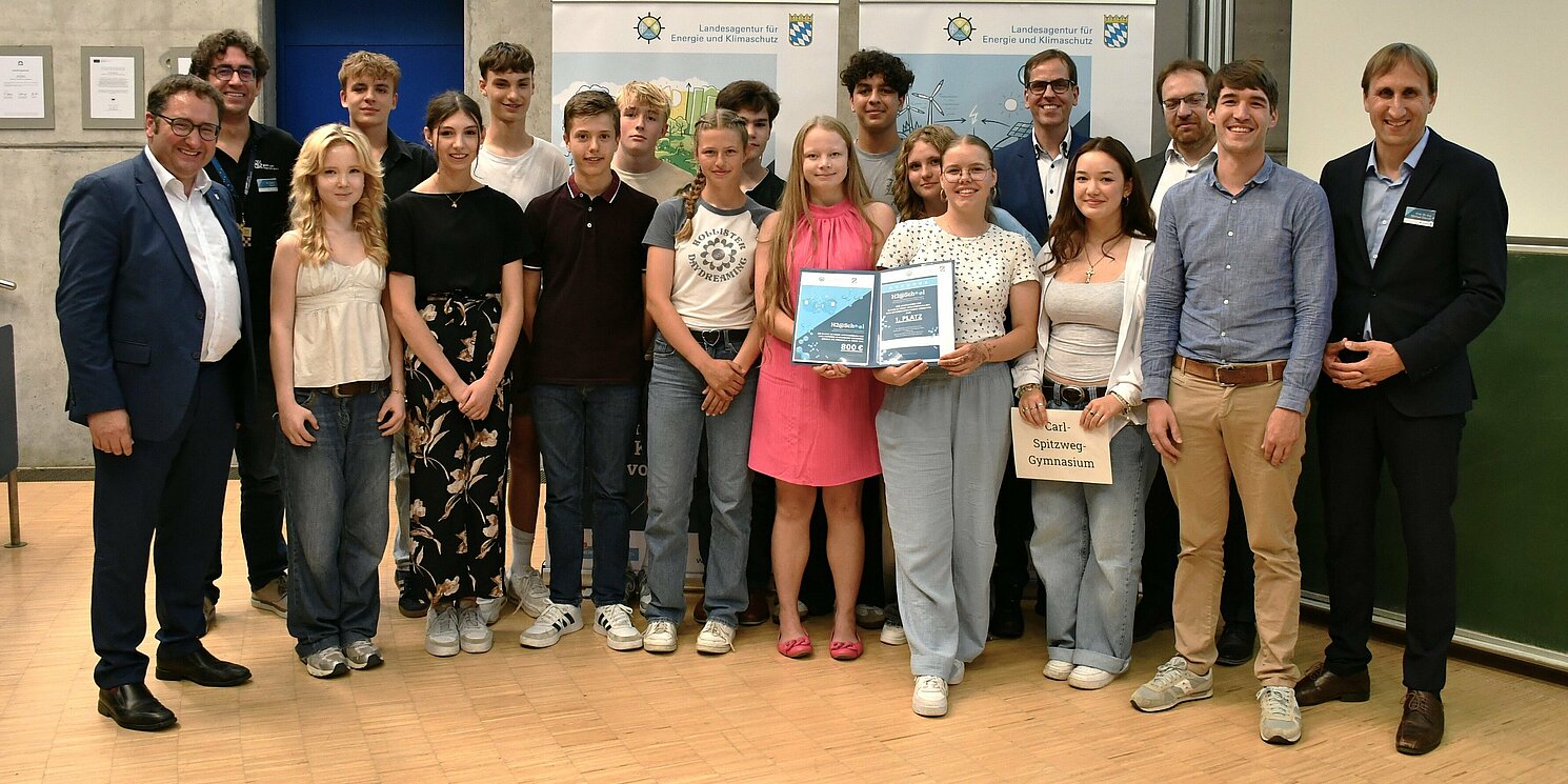 Das Siegerteam des Carl-Spitzweg Gymnasiums Germering mit Wirtschaftsstaatssekretär Tobias Gotthardt (links), Prof. Dr. Ralph Schneider, Präsident der OTH Regensburg (5. von rechts) sowie der Jury des Wasserstoff-Wettbewerbs. 